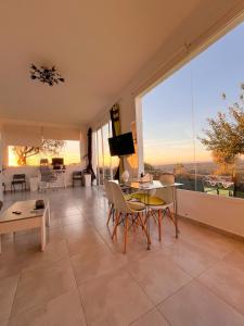 a living room with a table and chairs and a large window at El Coso Lodge & Workation in Zalamea la Real