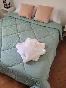uma cama com lençóis e almofadas verdes em Casa Oliva B & B em Mendoza