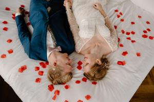 a bride and groom laying on a bed with hearts at Hotel de Timmerfabriek I Kloeg Collection in Vlissingen