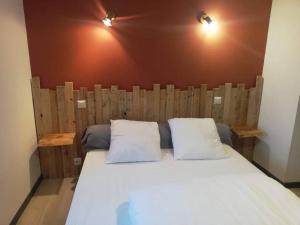 uma cama com uma cabeceira em madeira e 2 almofadas brancas em Maison au cœur du Sancy em Férérolles