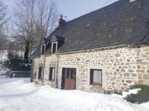 um edifício de pedra com um telhado preto na neve em Maison au cœur du Sancy em Férérolles