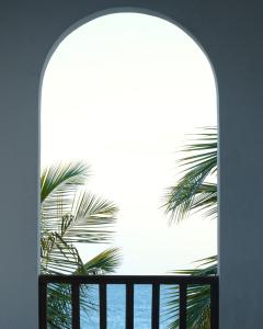 an arched window with a view of the ocean at Cardamon Hotel Nilaveli in Nilaveli