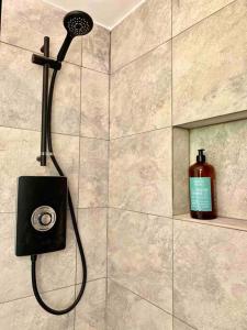 a bathroom with a shower with a bottle of soap at Lumin Lodge -Calm, cosy space near Norwich Airport in Horsham Saint Faith
