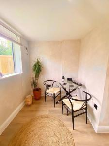 a living room with a table and chairs and a window at Lumin Lodge -Calm, cosy space near Norwich Airport in Horsham Saint Faith