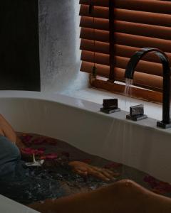a person in a bath tub with a water faucet at Cardamon Hotel Nilaveli in Nilaveli