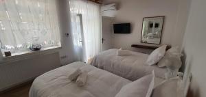 a white bedroom with two beds and a window at Bougainvillea House Lefkara in Pano Lefkara