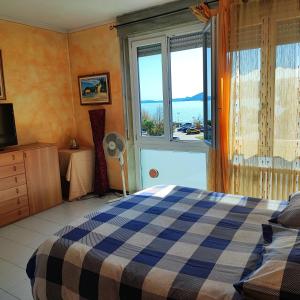 ein Schlafzimmer mit einem Bett und einem großen Fenster in der Unterkunft Appartamento Chic Vista Lago - Casa Janis in Verbania