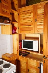 kuchnia z drewnianymi szafkami i kuchenką mikrofalową na ladzie w obiekcie Il Rifugio da Aldo - Rivisondoli w mieście Rivisondoli