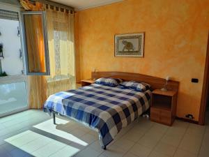 Appartamento Chic Vista Lago - Casa Janis في فيربانيا: غرفة نوم بسرير وبطانية منقوشة ونافذة