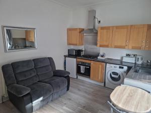 a living room with a couch and a kitchen at Lido Bay Ground Floor Apartment in Largs