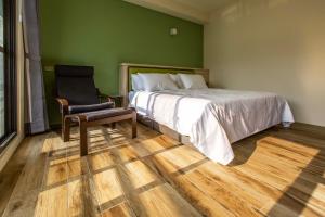 ein grünes Schlafzimmer mit einem Bett und einem Stuhl in der Unterkunft 晨煦行旅 in Lugu