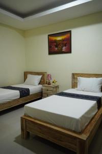 sypialnia z 2 łóżkami i zdjęciem na ścianie w obiekcie Umah Desa w mieście Banjarangkan