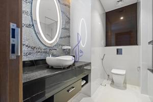 ein Badezimmer mit einem Waschbecken, einem WC und einem Spiegel in der Unterkunft Walaa Homes Luxury 2BR at DAMAC Esclusiva Tower Riyadh-3104 in Riad