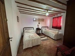 1 Schlafzimmer mit 2 Betten und einem roten Fenster in der Unterkunft Casa Rural La Quinta Del Poeta 