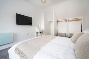 a white bedroom with a bed and a flat screen tv at 3 King Charles Court, Sudbury in Sudbury