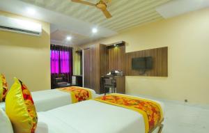 a hotel room with two beds and a tv at Hotel New Majestic in Ajmer