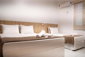 um quarto de hotel com duas camas com almofadas brancas em Pousada Areia do Forte em Cabo Frio