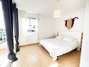 - une chambre blanche avec un lit et une fenêtre dans l'établissement La Milagrosa Surf House & CoWork, à Lajares