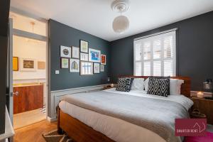 a bedroom with a large bed with blue walls at Kingston upon Thames - 3 Bedroom House in Kingston upon Thames