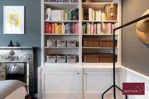 a book shelf filled with books next to a fireplace at Kingston upon Thames - 3 Bedroom House in Kingston upon Thames