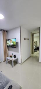 ein Wohnzimmer mit einem TV an der Wand und einem Tisch in der Unterkunft Moderno Apartamento muy cerca de Cali in Jamundí