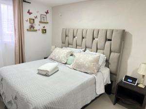 1 dormitorio con 1 cama grande con sábanas y almohadas blancas en Moderno Apartamento muy cerca de Cali, en Jamundí