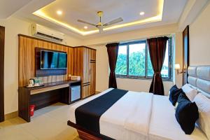 una camera d'albergo con letto e TV di OYO Palette - The Grand Aryans Hotel a Calcutta