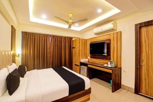 a hotel room with a bed and a flat screen tv at OYO Palette - The Grand Aryans Hotel in Kolkata