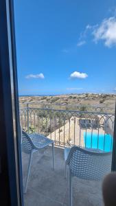 a balcony with two chairs and a swimming pool at Sea Holly Gozo in Nadur