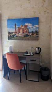 a desk with a chair and a painting on a wall at Sea Holly Gozo in Nadur