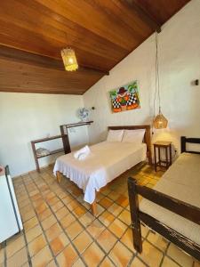 a bedroom with a bed and a bench in a room at Pousada Casa Feliz Maxaranguape in Maxaranguape