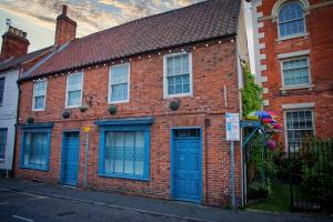 ein Backsteinhaus mit blauen Türen auf einer Straße in der Unterkunft The Secret Garden in Newark upon Trent