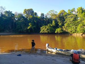 une personne debout à côté d'un bateau sur une rivière dans l'établissement WaitaAmazonlodge, 