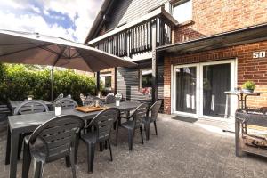 a table with chairs and an umbrella on a patio at Pension Haus am Kohfurth in Norderstedt