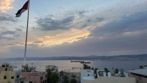 a flag on a pole in front of a body of water at ArwaHotel Apartments اروى للشقق الفندقية in Aqaba