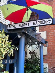 ein Schild für den geheimen Garten unter einem bunten Schirm in der Unterkunft The Secret Garden in Newark upon Trent