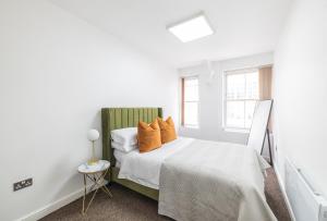 ein Schlafzimmer mit einem Bett mit orangefarbenen Kissen darauf in der Unterkunft The Olive Green Loft in Leicester