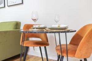 einen Esstisch mit orangefarbenen Stühlen und Gläsern Wein in der Unterkunft The Olive Green Loft in Leicester
