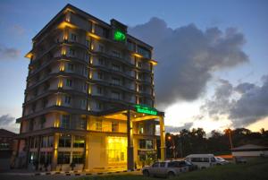 wysoki budynek z zielonym znakiem na górze w obiekcie The Pavilion Hotel w mieście Sandakan