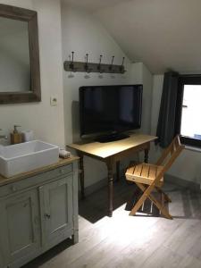 een badkamer met een televisie en een bureau met een wastafel bij Petite maison Liégeoise «la cabane de Liège» in Luik