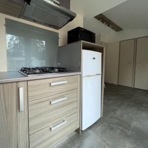 a kitchen with a stove and a white refrigerator at Mobilehome lumineux 2 chambres - 4 personnes - Proche Europa Park in Boofzheim