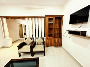 uma sala de estar com duas cadeiras e uma televisão em Thrissur Villas Home Stay em Thrissur