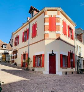 a building with red shutters and a red door at Maison Jeanne d’Arc in Mennetou-sur-Cher