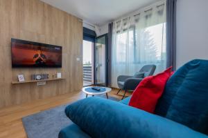 a living room with a blue couch and a tv at Vila Pekovic Central-Apartman PAMA in Zlatibor