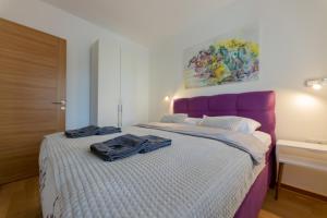 una camera con un grande letto con testiera viola di Vila Pekovic Central-Apartman PAMA a Zlatibor