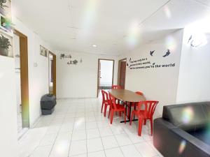 a dining room with a table and red chairs at Sea & Wave #1 Coral Bay Apartment in Pangkor