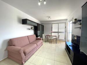 un soggiorno con divano rosa e tavolo di Apartamentos Medano - La Ladera a El Médano