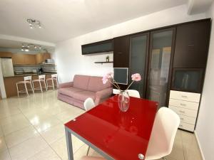 un soggiorno con tavolo rosso e divano rosa di Apartamentos Medano - La Ladera a El Médano