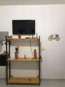 a tv on a shelf with a television on a wall at Cantinho da mery 1 in Maragogi