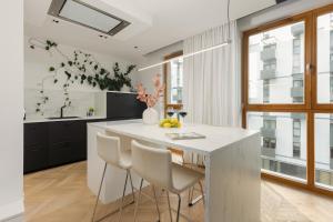 una cocina con una gran isla blanca con sillas en Elegant Apartment Kasprzaka in Wola by Renters Prestige en Varsovia